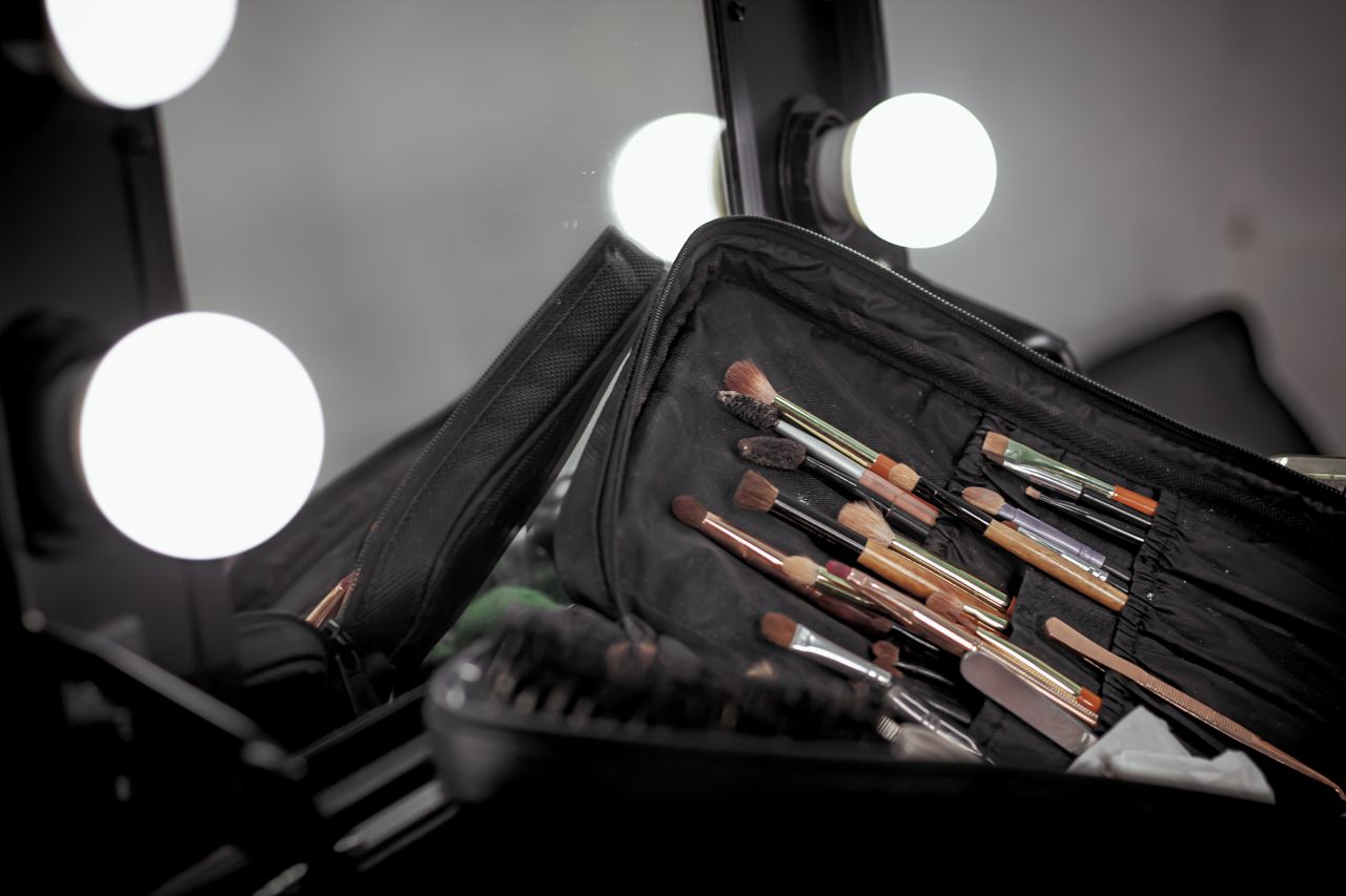 A set of makeup brushes on a vanity table with bright lights, perfect for beauty and fashion themes.